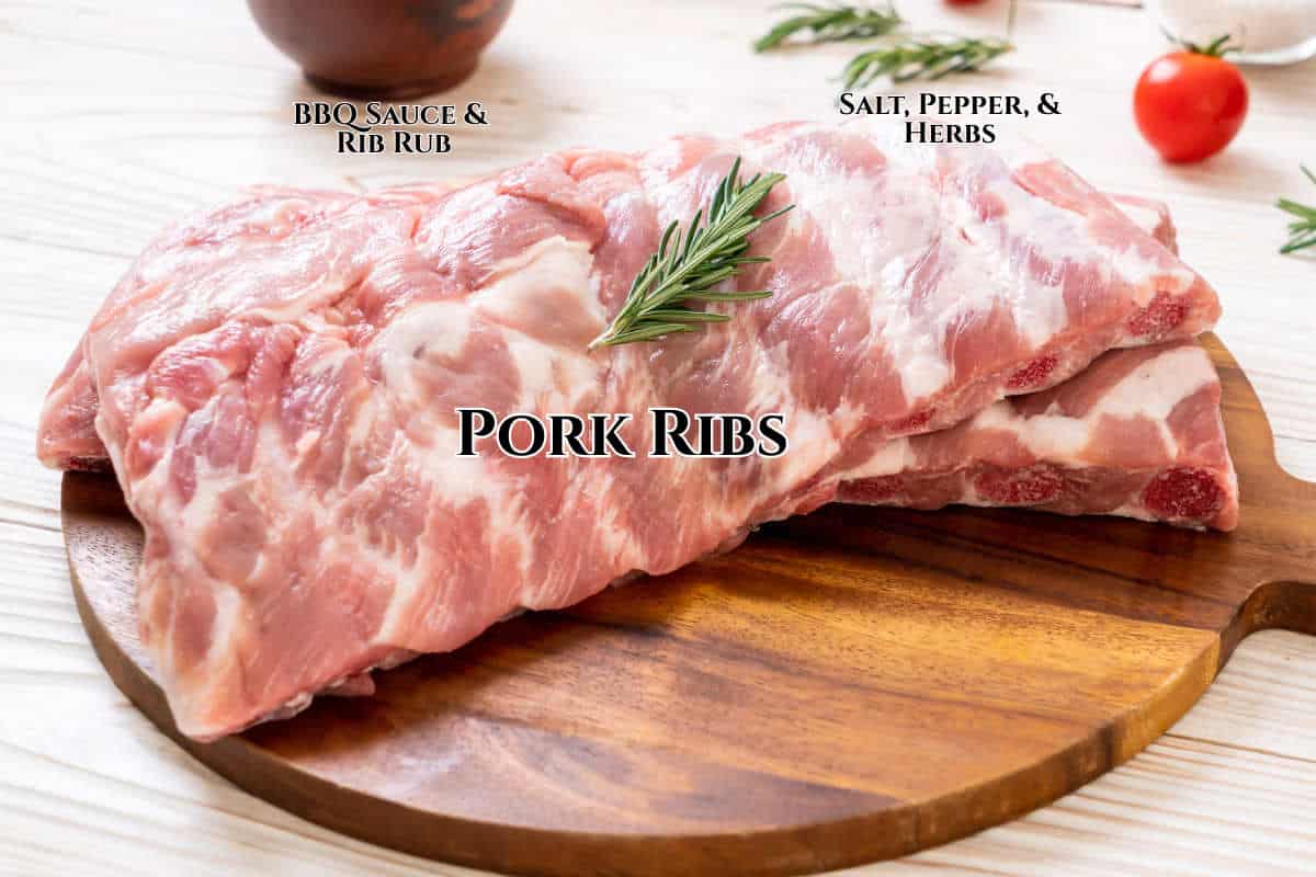 Raw pork ribs stacked on a round wooden cutting board, garnished with a sprig of rosemary. Text labels indicate "BBQ Sauce & Rib Rub," "Salt, Pepper, & Herbs," and "Pork Ribs." Tomatoes and herbs are in the background.