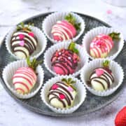 chocolate covered strawberries in white paper cups.