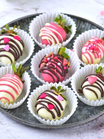 chocolate covered strawberries in white paper cups.