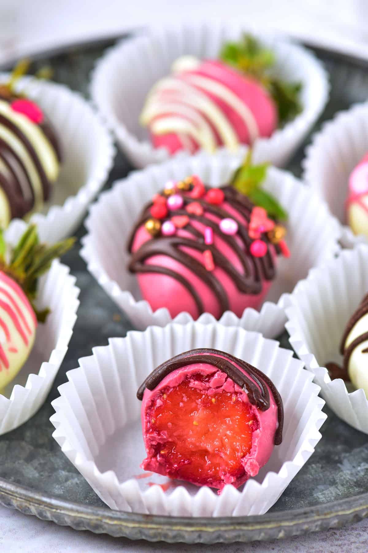 A group of chocolate covered strawberries in paper cups.