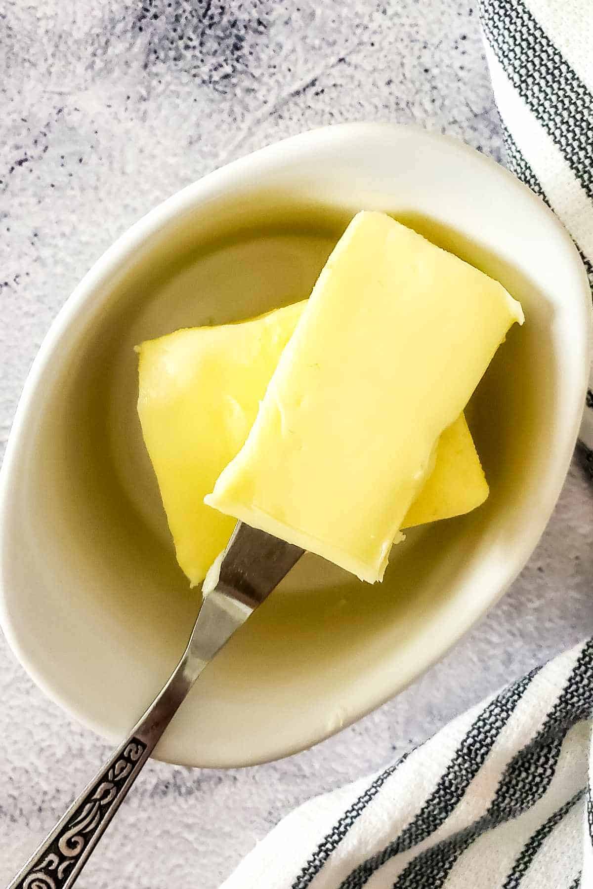 A close-up of two pats of cultured butter in a white dish.