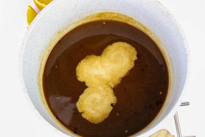 Orange teriyaki sauce thickening in a saucepan.