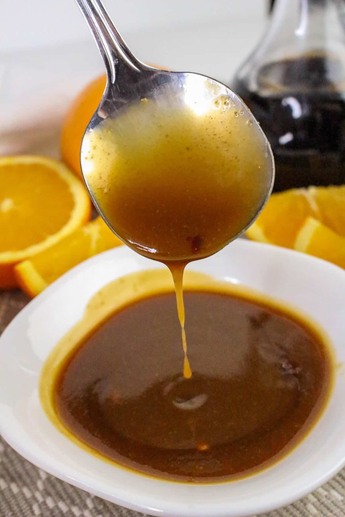 Orange teriyaki sauce being poured into a white bowl.