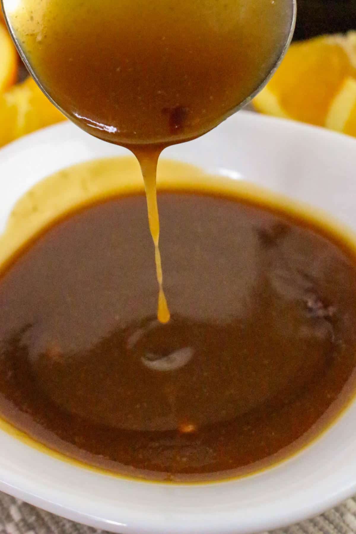 Orange teriyaki sauce being drizzled into a white bowl.