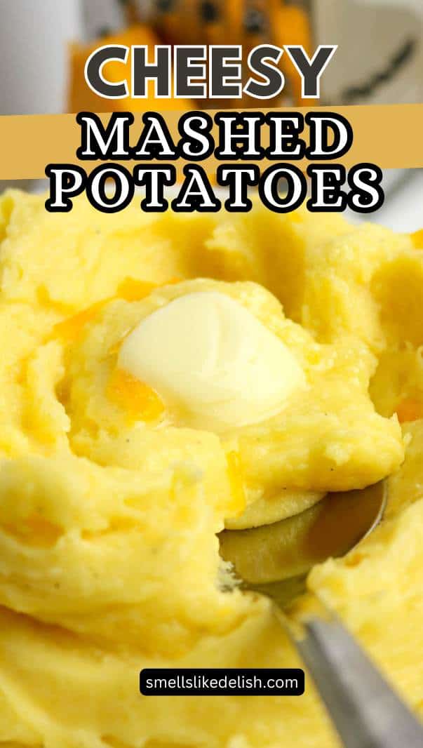 A close-up of creamy, yellow mashed potatoes with melted cheese and a pat of butter on top, with a spoon scooping some out. Text overlay says "Cheesy Mashed Potatoes.