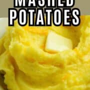 A bowl of creamy yellow mashed potatoes topped with a pat of melting butter, labeled "Cheesy Mashed Potatoes" with the website smellslikedelish.com shown at the bottom.