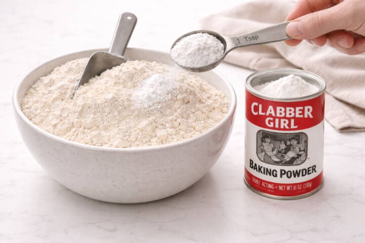 Baking powder added to mixing bowl of all-purpose flour.