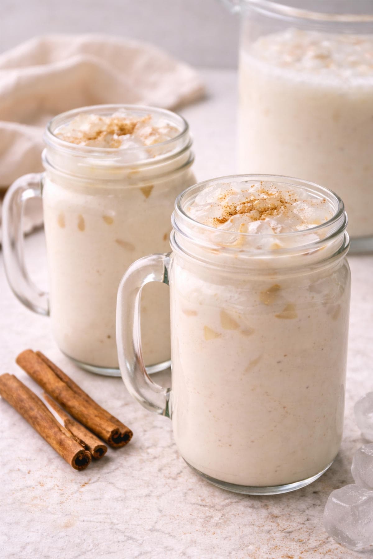 Glass of creamy horchata over ice with cinnamon sticks.