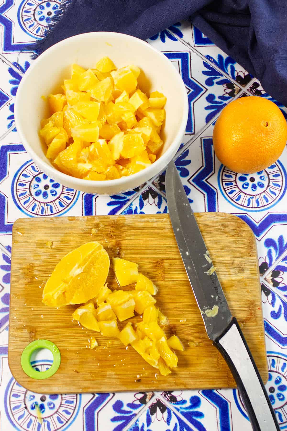 A bowl of oranges and a knife on a cutting board, ready for slicing to make fresh orange marmalade.