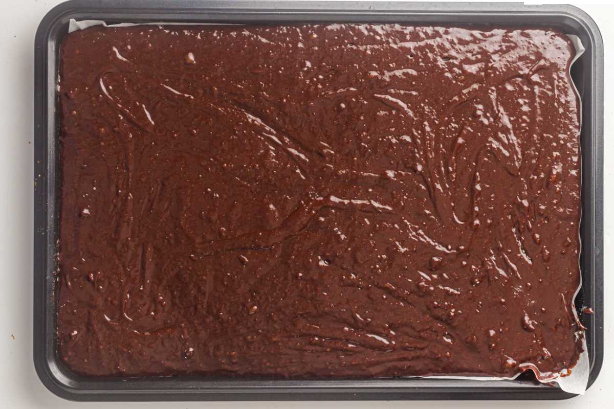 Brownie batter spread evenly in a sheet pan before baking.