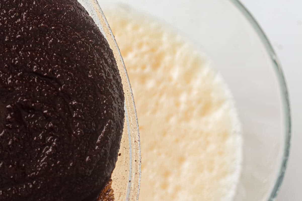 Chocolate mixture being poured into beaten eggs for brownie batter.