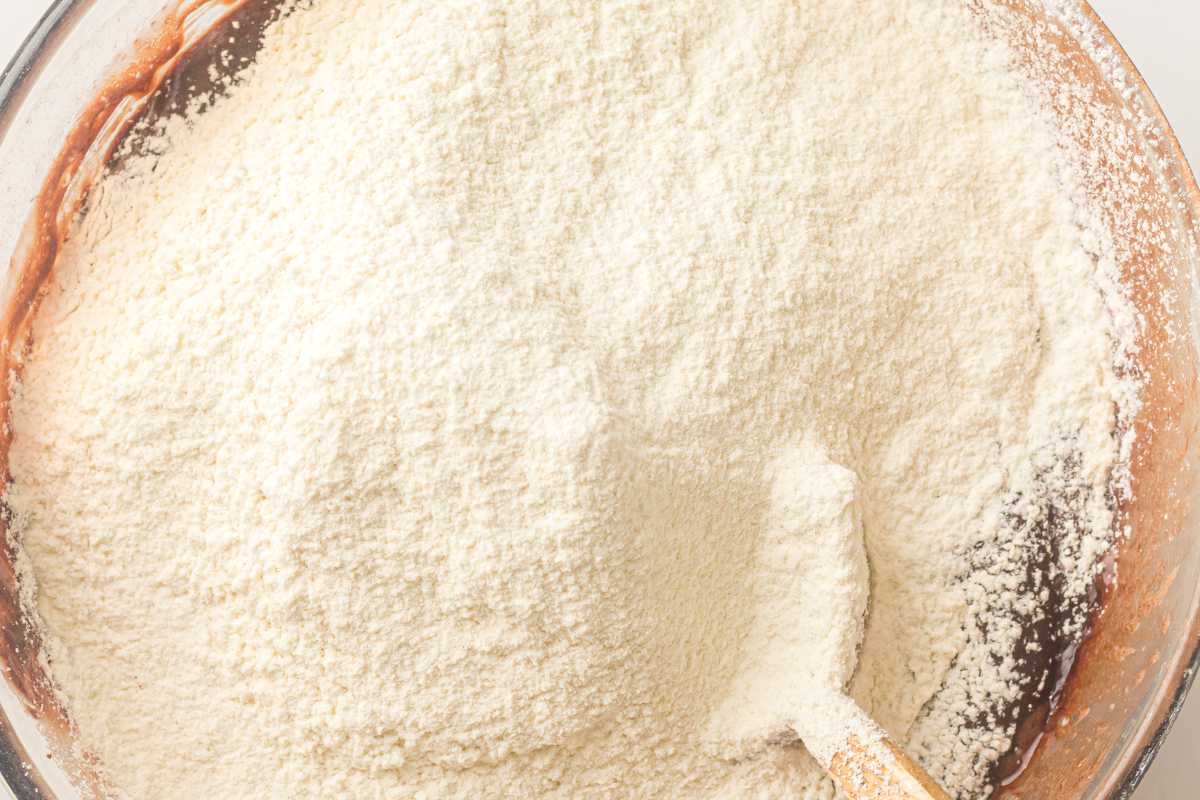 Flour being folded into brownie batter until just combined.