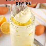 A wooden spoon scoops homemade mayonnaise from a glass jar. Fresh lemons, eggs, and a striped kitchen towel are visible in the background. Text reads “Basic Mayonnaise Recipe” and “smellslikedelish.com.”.