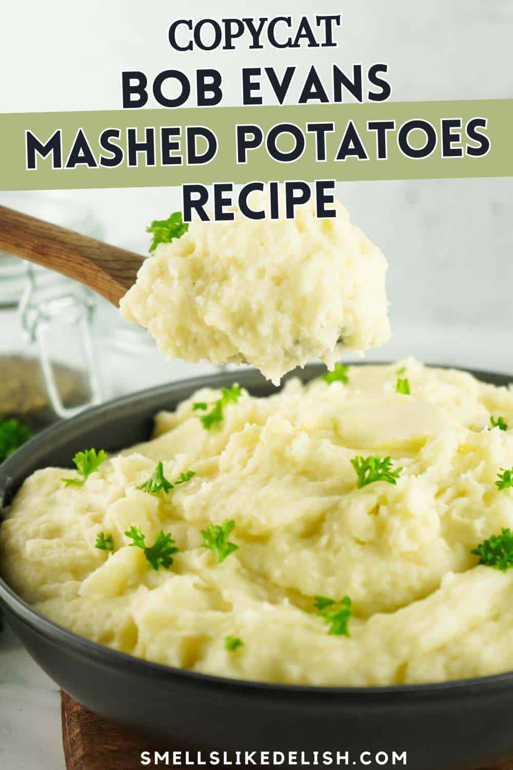 A bowl of creamy mashed potatoes garnished with parsley, with a wooden spoon lifting a spoonful. Text over the image reads "Copycat Bob Evans Mashed Potatoes Recipe.