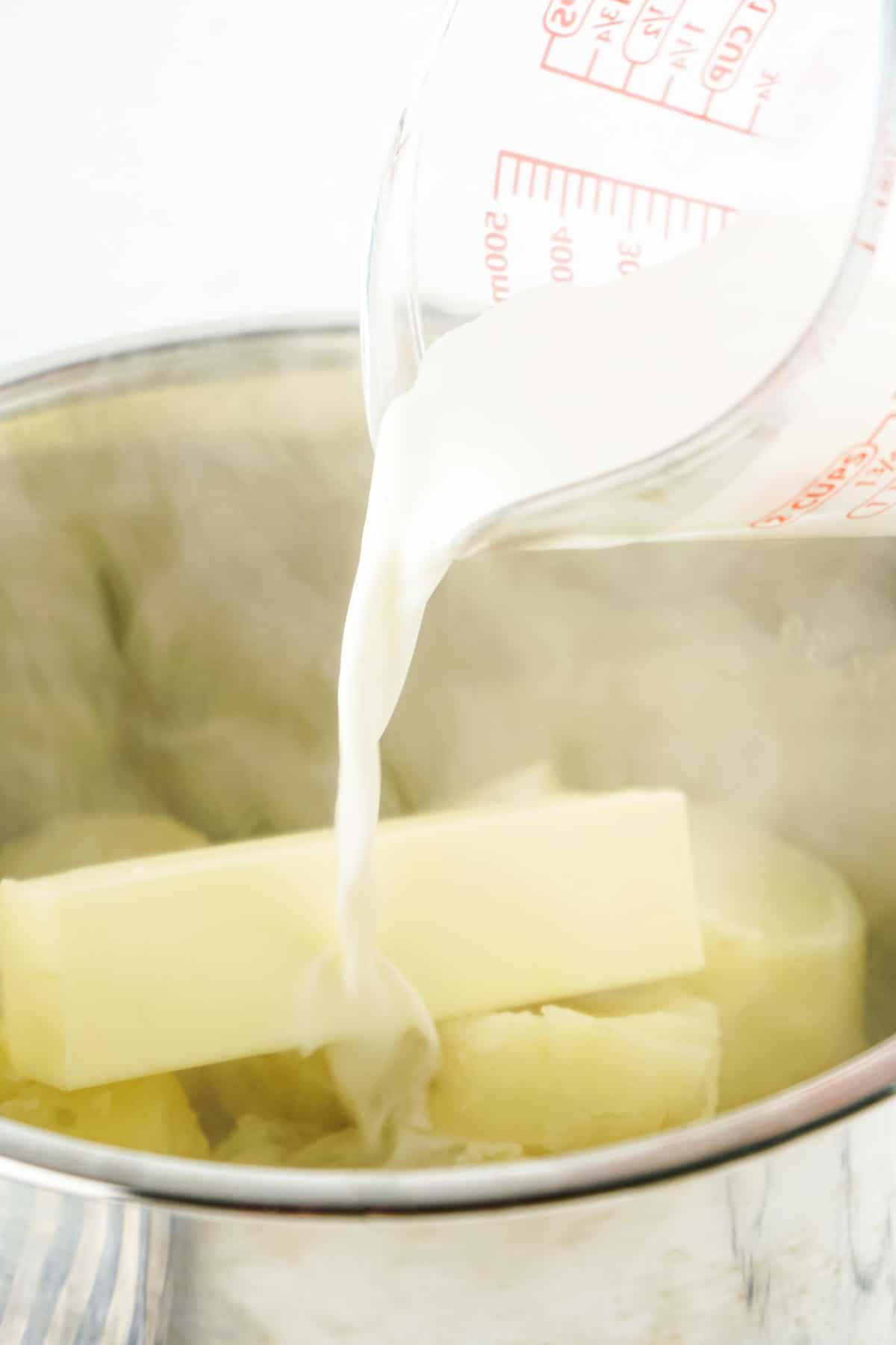 Milk being poured into cooked potatoes and butter in an Instant Pot for copycat Bob Evans mashed potatoes.