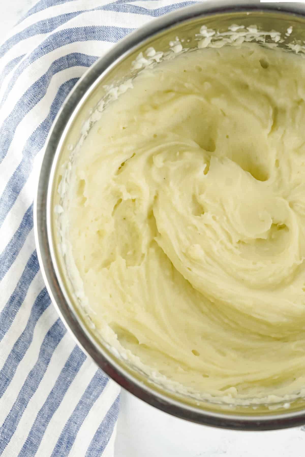 Creamy copycat Bob Evans mashed potatoes in a stainless steel bowl on a white surface.