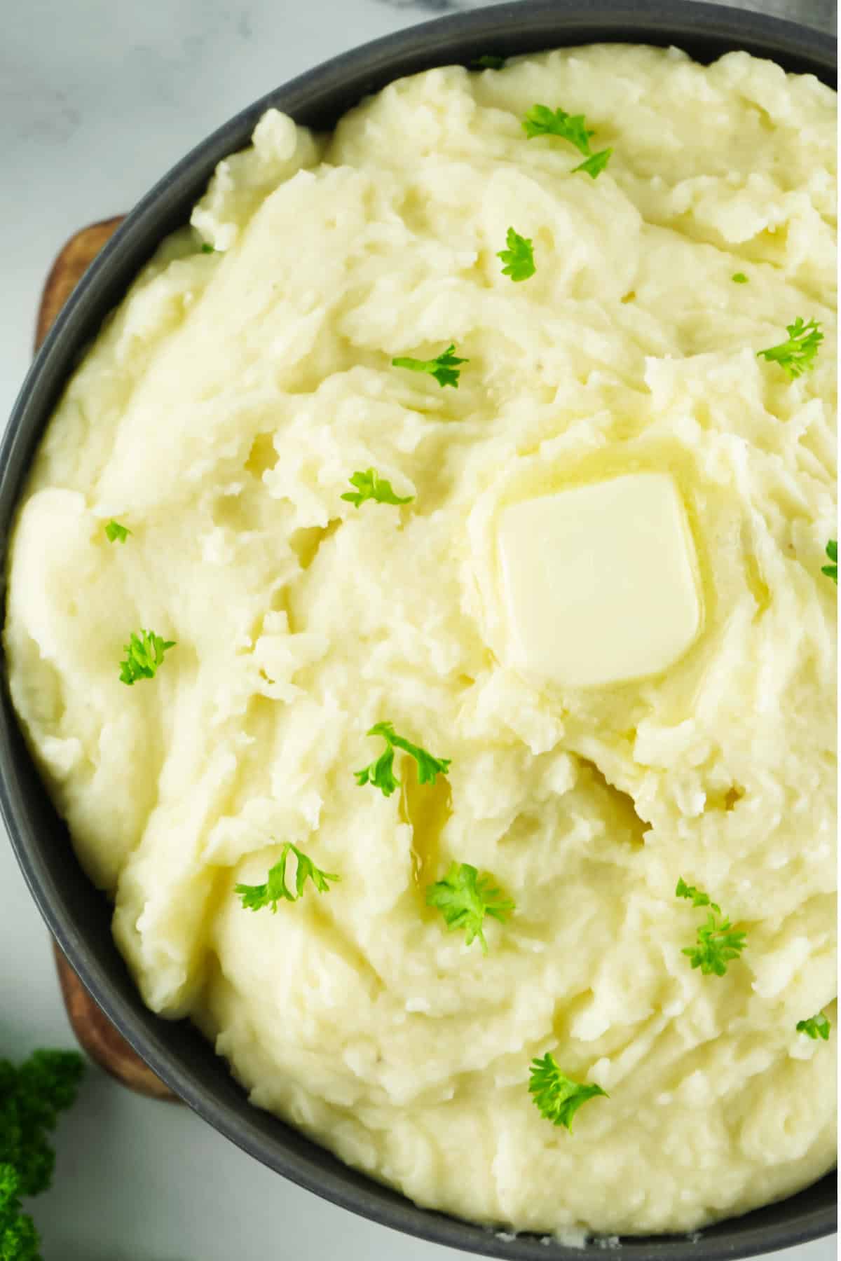 A bowl of creamy copycat Bob Evans mashed potatoes made in the Instant Pot and garnished with fresh parsley.