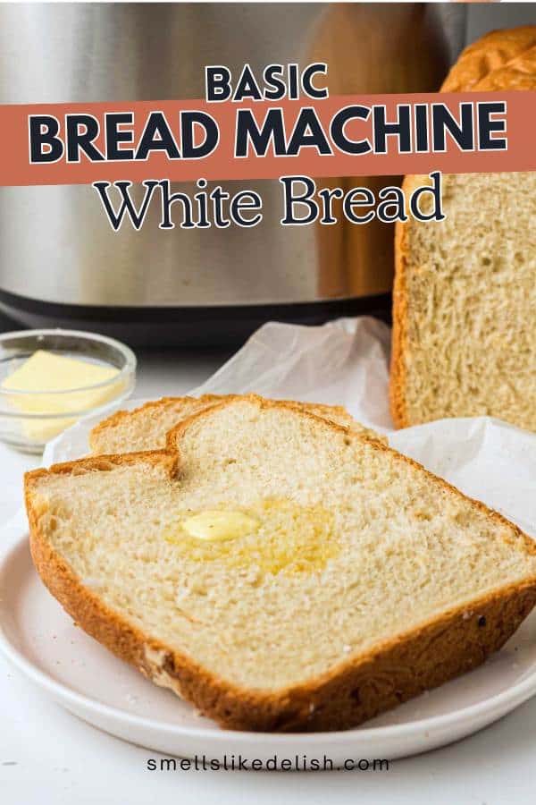 A thick slice of homemade white bread with melted butter sits on a plate, next to a full loaf and a small bowl of butter, in front of a bread machine. Text reads "Basic Bread Machine White Bread.