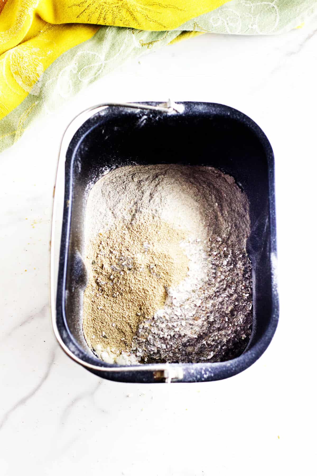 A bread machine pan filled with flour and yeast.