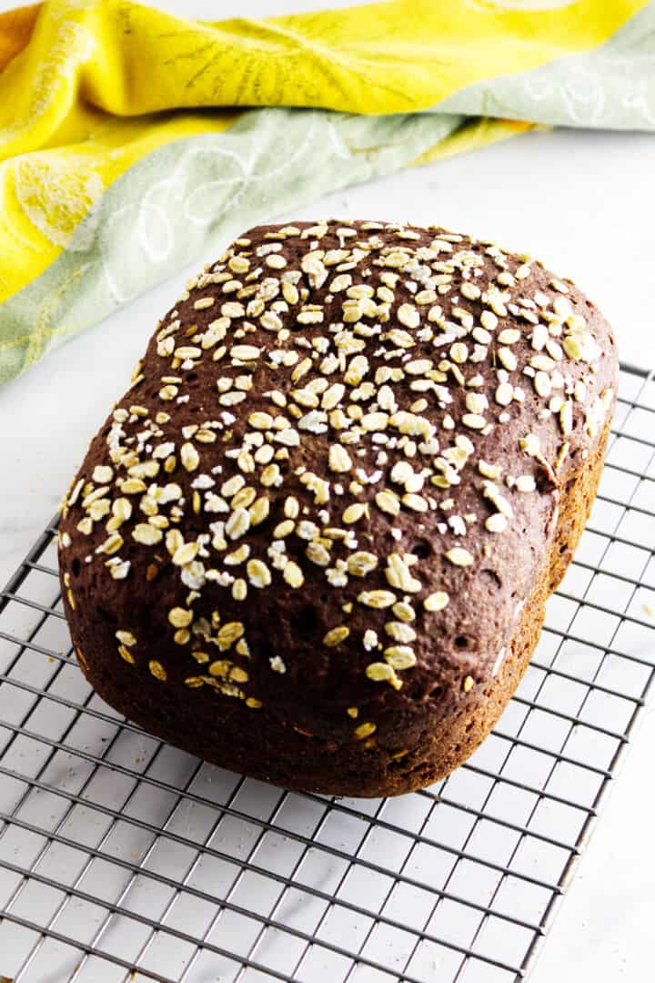 Finished brown bread loaf cooling on rack.