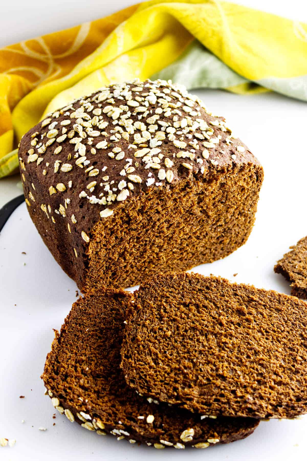 Sliced loaf of bread machine brown bread on cutting board.