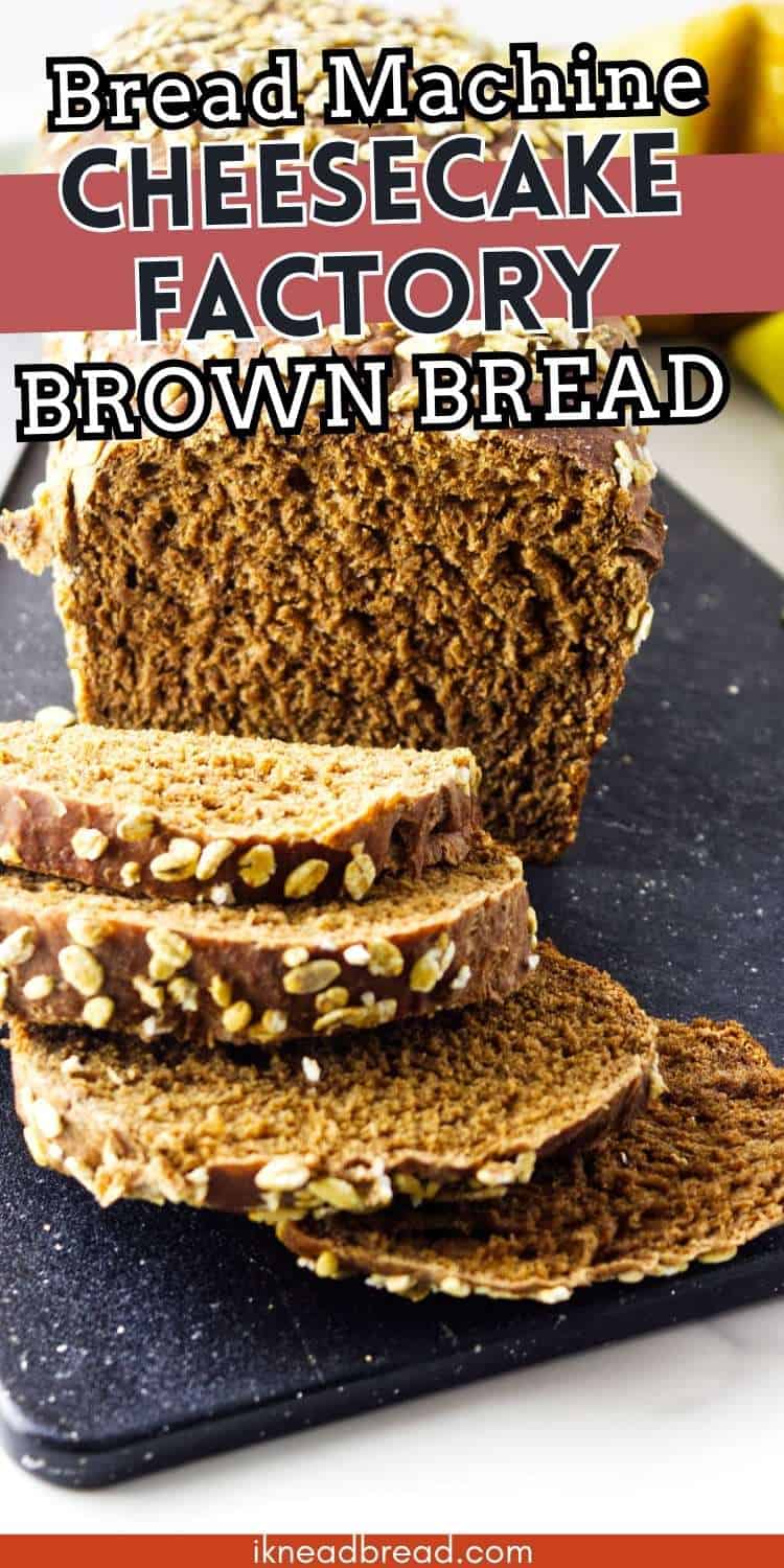 Sliced loaf of dark brown bread topped with oats on a black cutting board, with text: "Bread Machine Cheesecake Factory Brown Bread.