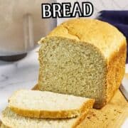 A loaf of oatmeal bread, partially sliced, sits on a wooden cutting board next to a bread machine. Text overlay reads "Bread Machine Oatmeal Bread.