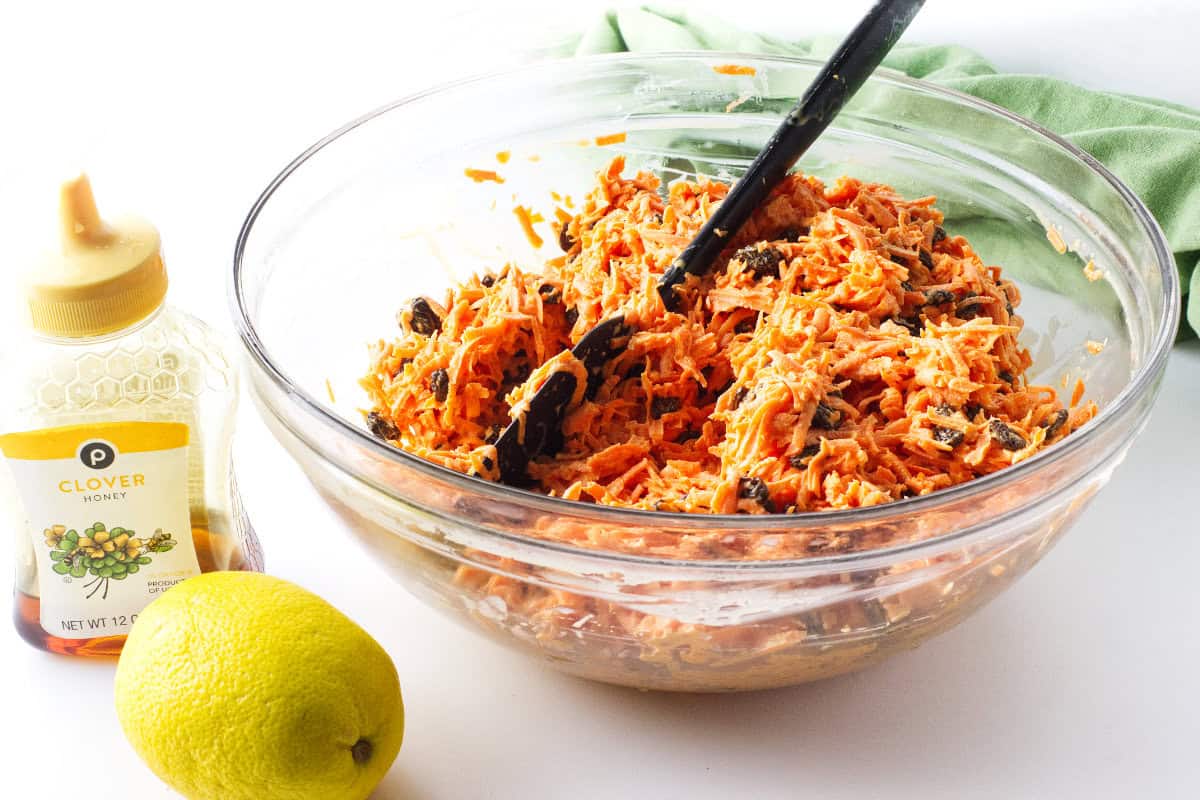 Chick-fil-A carrot raisin salad ingredients being mixed in a bowl with creamy dressing.
