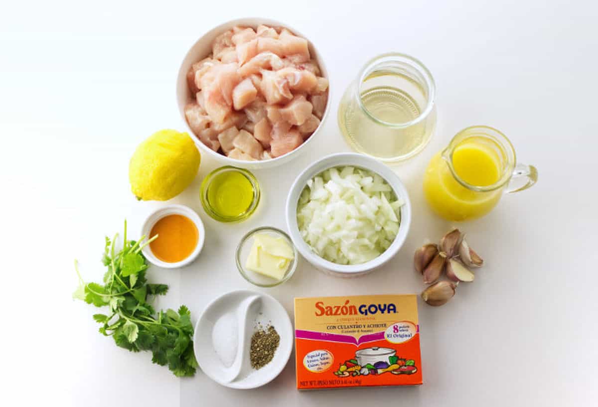 Ingredients for Chicken Mozambique including cubed chicken, onion, garlic, lemon, cilantro, broth, butter, oil, and seasoning packets.