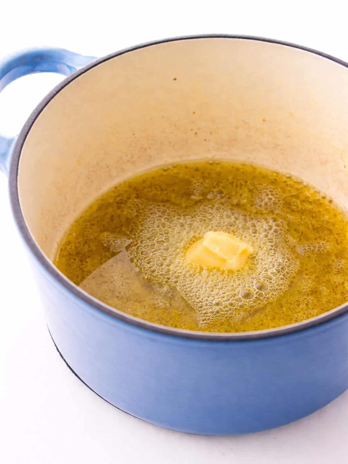 Olive oil and butter melting in a blue Dutch oven..
