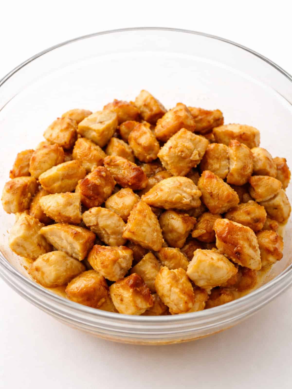 Lightly browned chicken pieces set aside in a bowl..