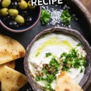 A bowl of homemade labneh topped with olive oil and herbs sits on a dark tray, served with pita wedges, olives, and parsley. Text reads "Homemade Labneh Recipe" at the top.