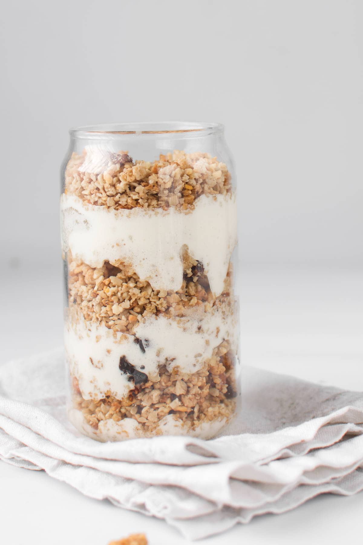 A clear glass jar layered with homemade Greek yogurt and granola.