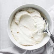 A bowl filled with freshly make homemade Greek yogurt, with a spoon on top of the mixture.