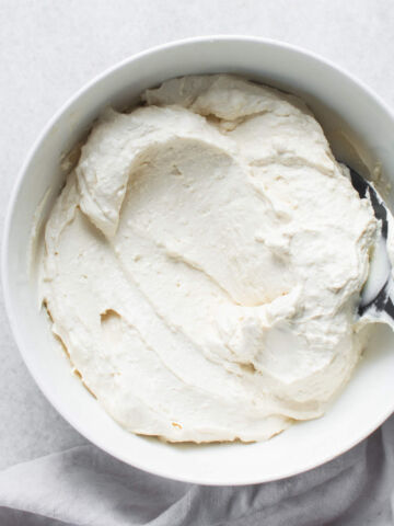 A bowl filled with freshly make homemade Greek yogurt, with a spoon on top of the mixture.