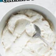 A bowl of thick Greek yogurt with a spoon inside, showing a heart shape in the yogurt. Text above reads “How to Make Homemade Greek Yogurt.” Website "smellslikedelish.com" is at the bottom.