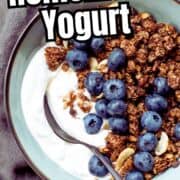 A glass of homemade yogurt topped with granola and chocolate chips on a table with a spoon, with the text “How to make homemade yogurt” above. A jar of granola is in the background.