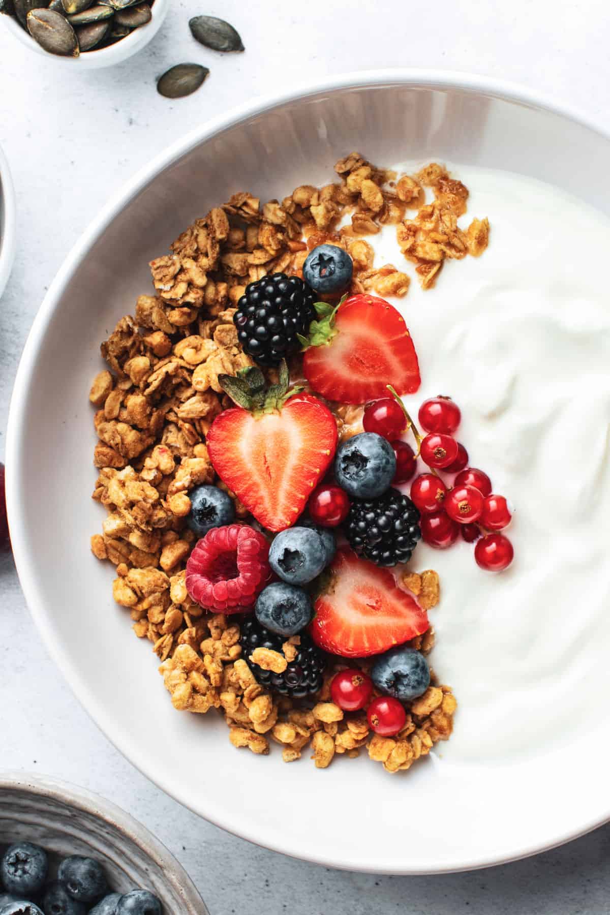 A bowl of homemade lactose free yogurt topped with granola and fresh berries.