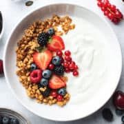 A bowl of lactose free yogurt topped with granola and fresh berries.
