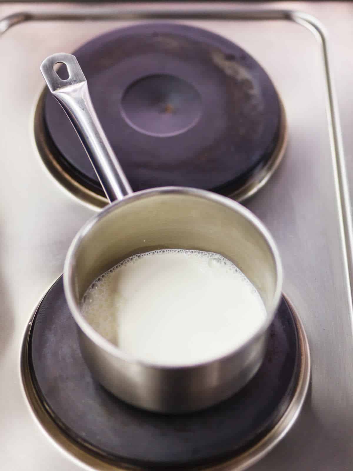 Warming lactose free milk in a saucepan on the stove.
