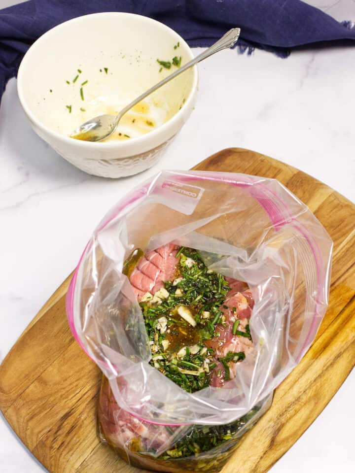 Pouring marinade over lamb in zip-top bag.