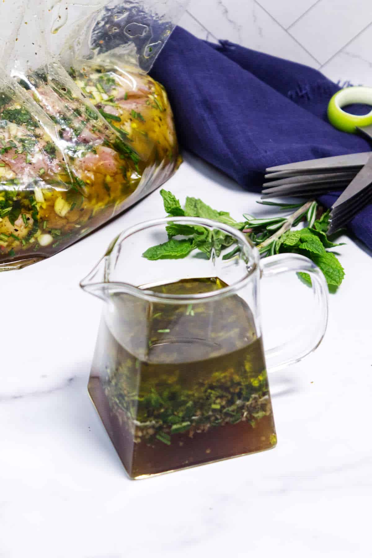 Herb lamb marinade with garlic and mint next to marinating lamb in bag.