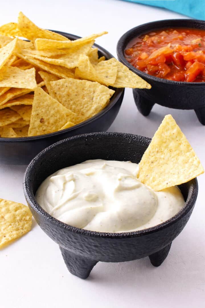 Close up of Mexican white sauce dip with tortilla chip for dipping.