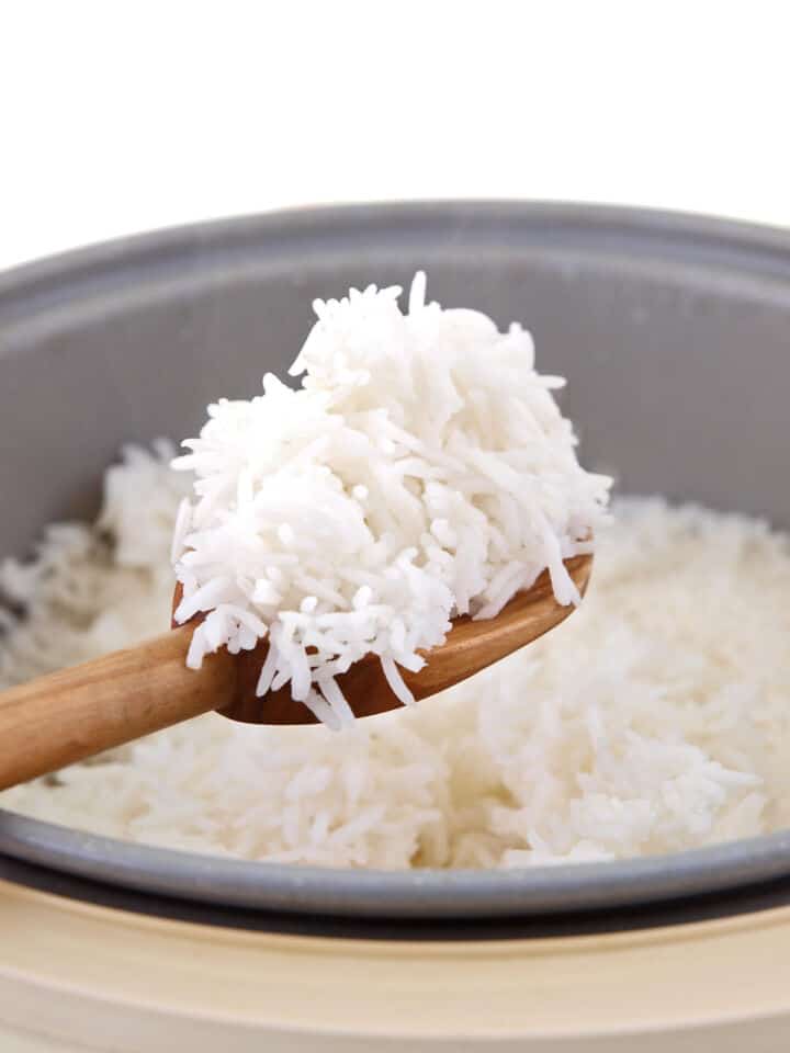 Fluffing cooked basmati rice with a spoon to separate long grains.