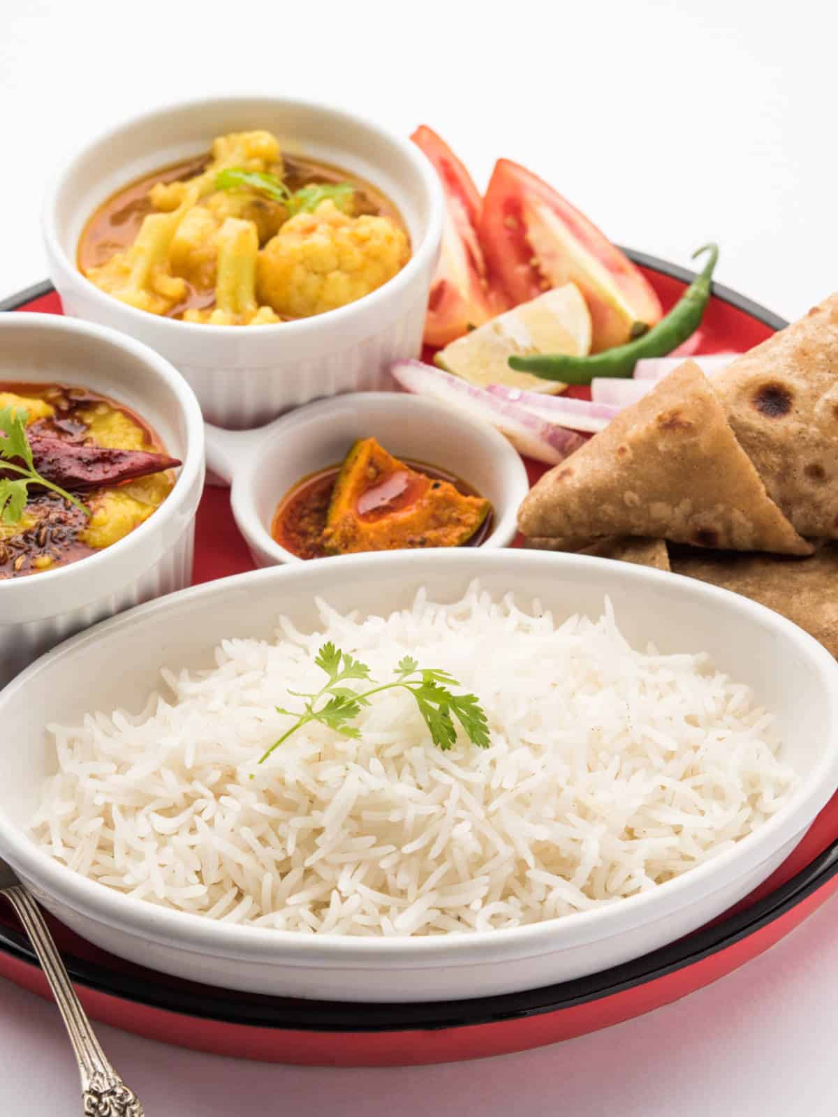 Basmati rice served with Indian curry, naan, and vegetable side dishes.