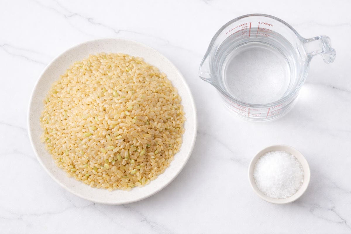 Short grain brown rice, water, and salt measured for rice cooker recipe.