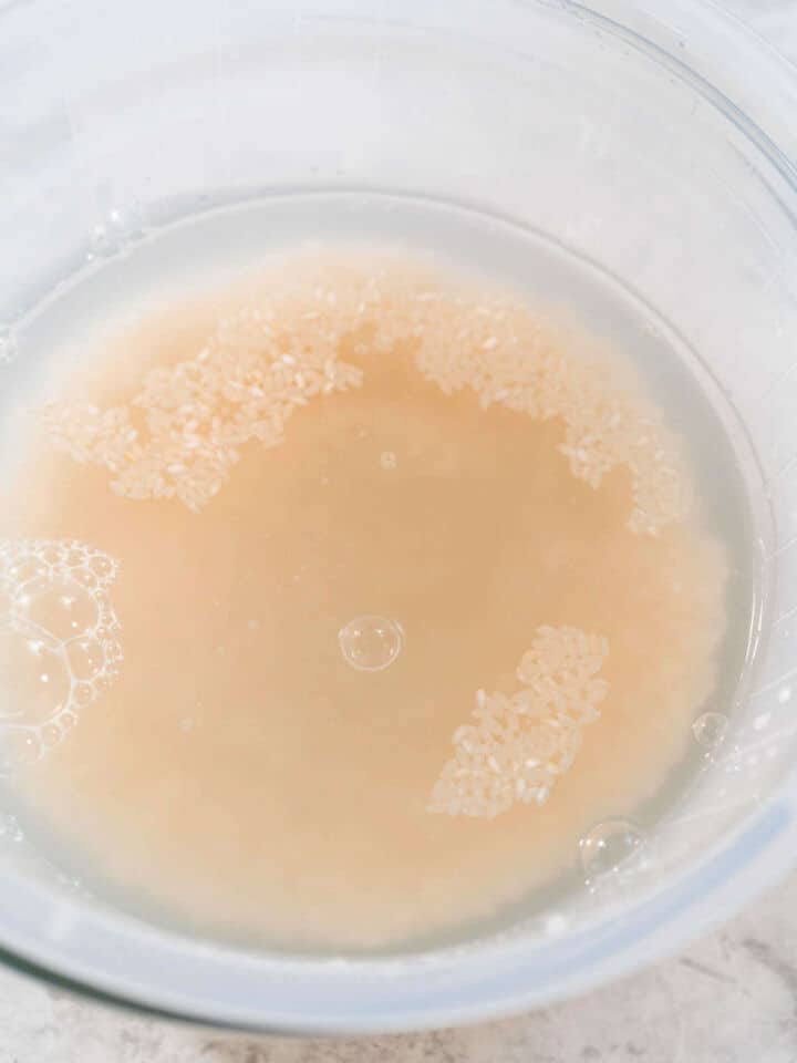 Rinsing short grain brown rice in water to remove excess starch.