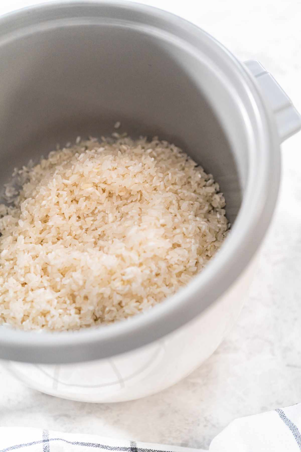 Rinsed long-grain white rice in rice cooker pot before cooking..