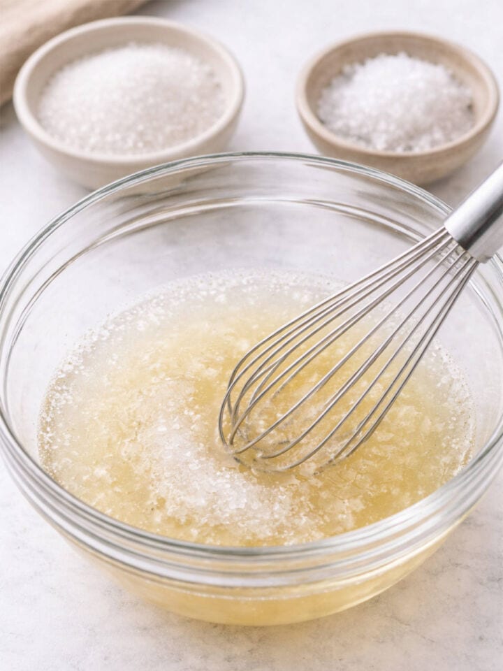 Whisking rice vinegar, sugar, and salt in a bowl.