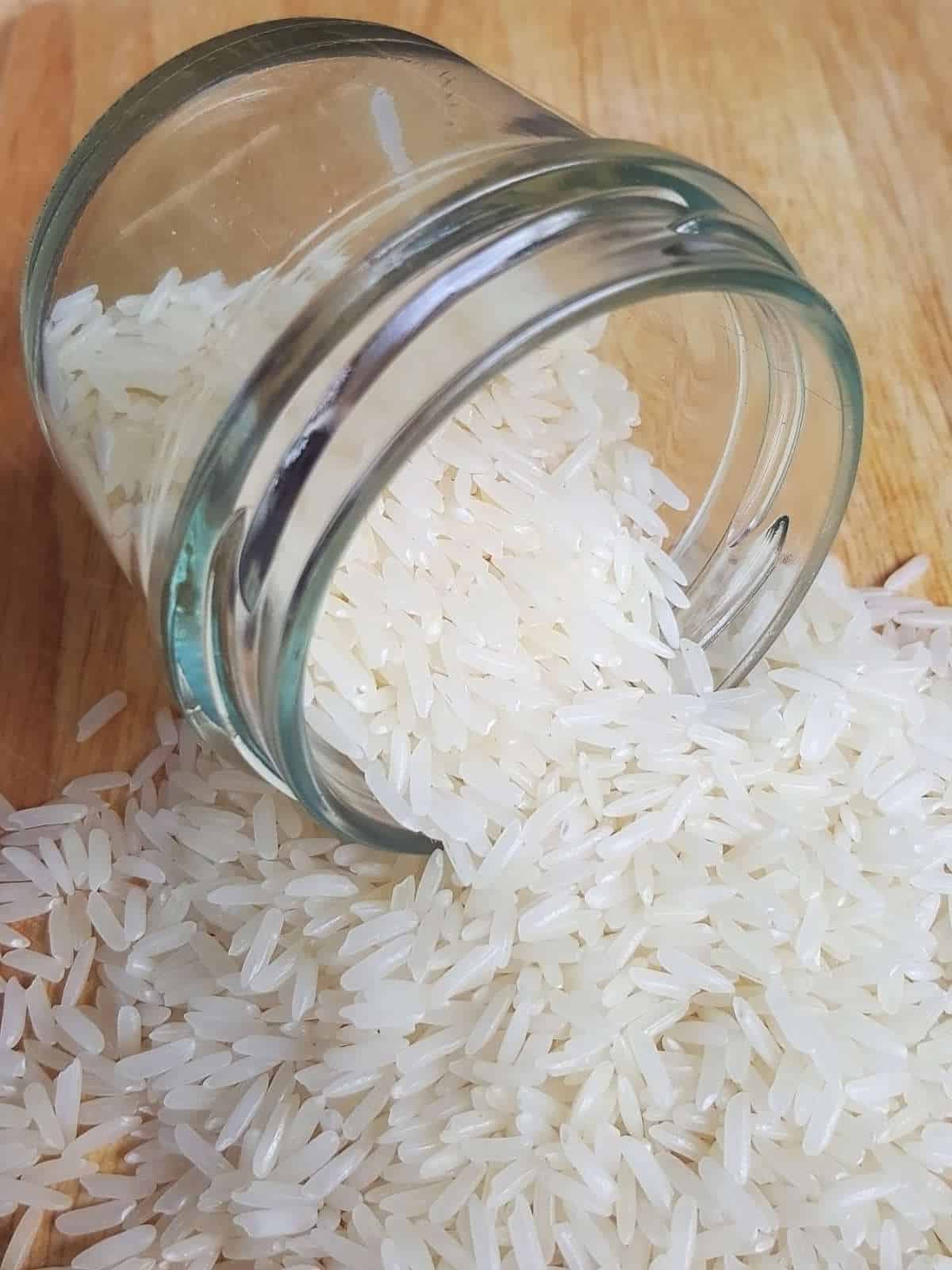 Uncooked jasmine rice grains on wooden surface.
